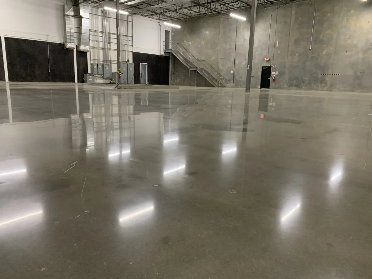 Sealed concrete floor reflecting overhead lights in an open warehouse